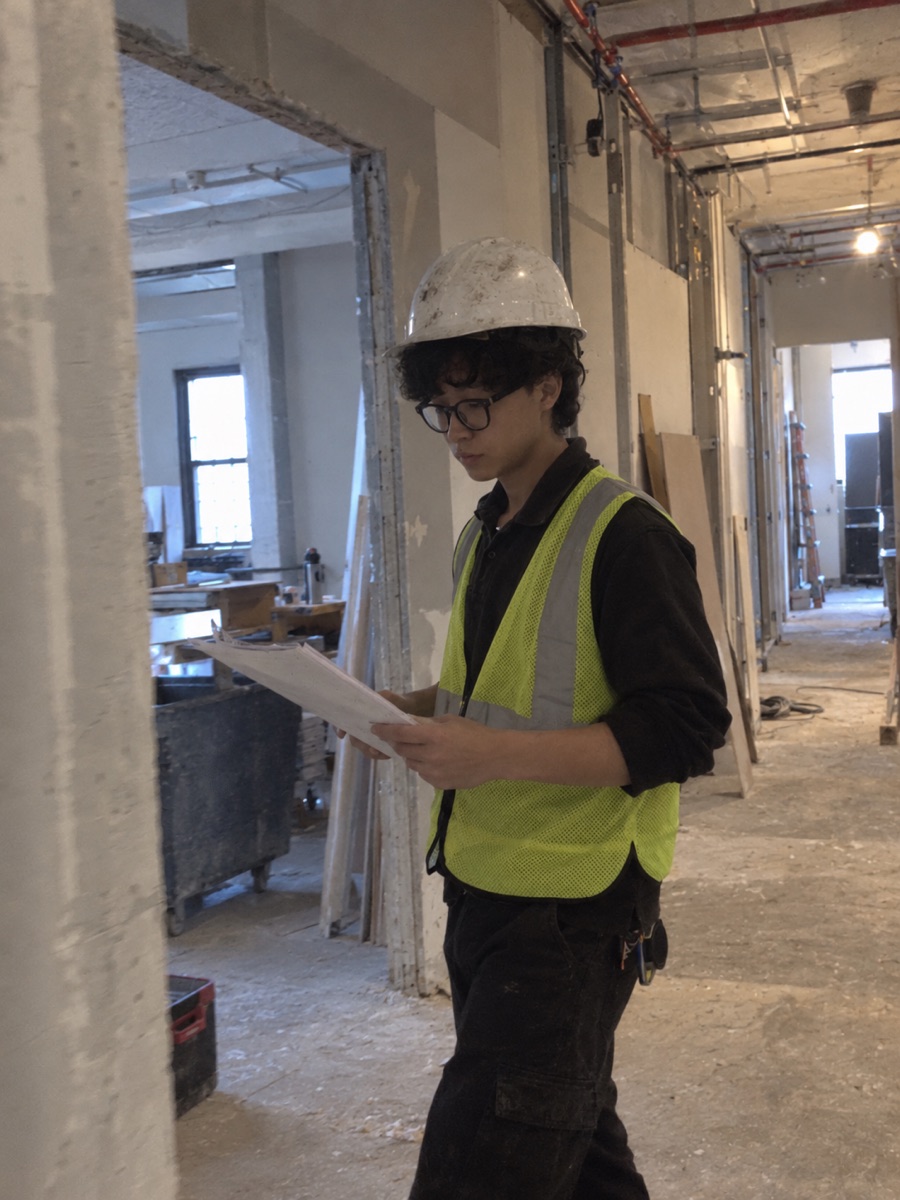 Junhong Liao reading drawings on a renovation job site